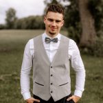 Julian Hafemann steht draußen in der Natur mit Hemd und Fliege.