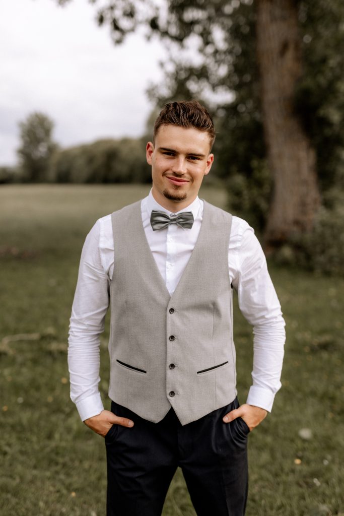 Julian Hafemann steht draußen in der Natur mit Hemd und Fliege.